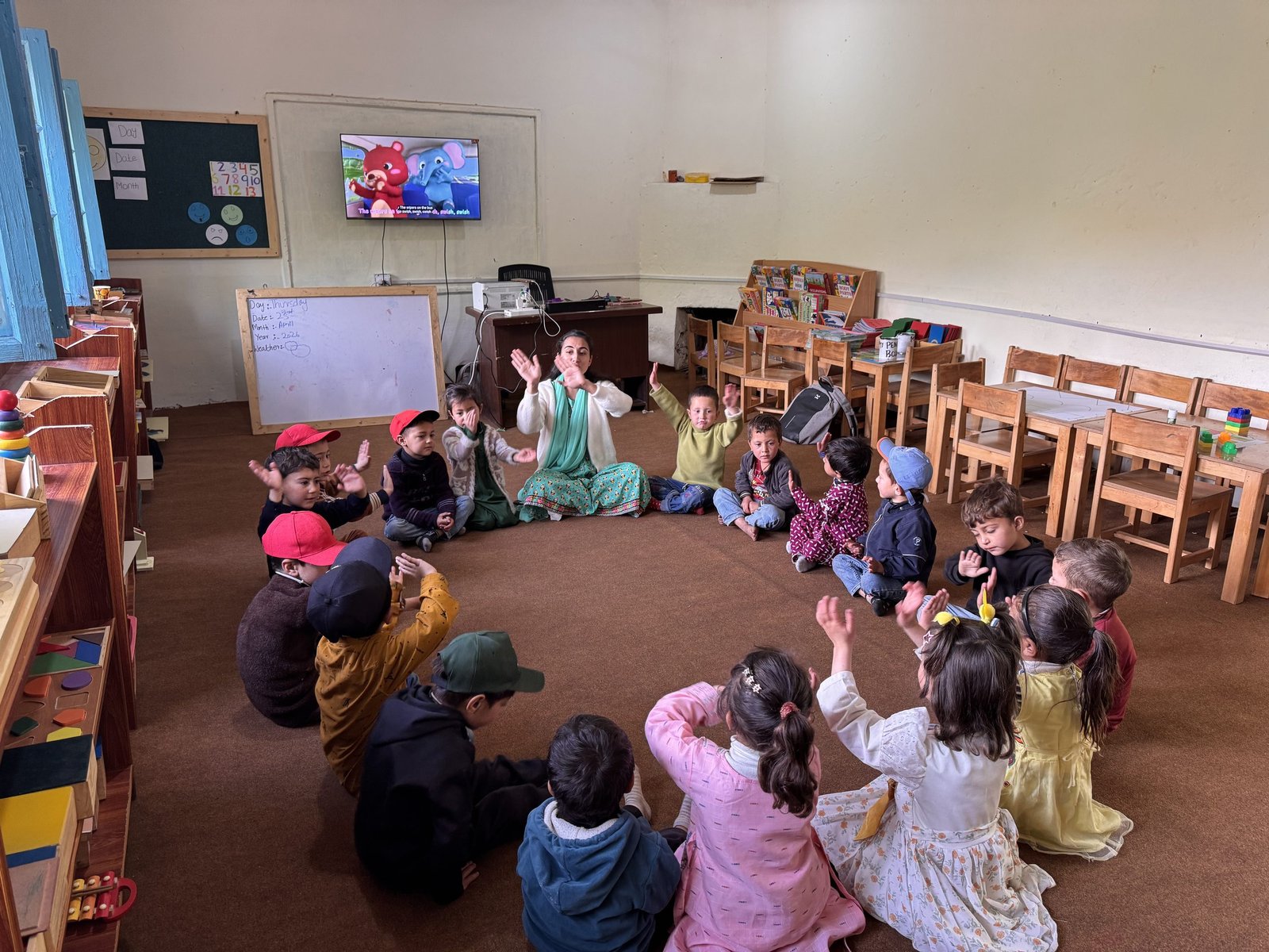 Children and their teacher clap along together during an action song.