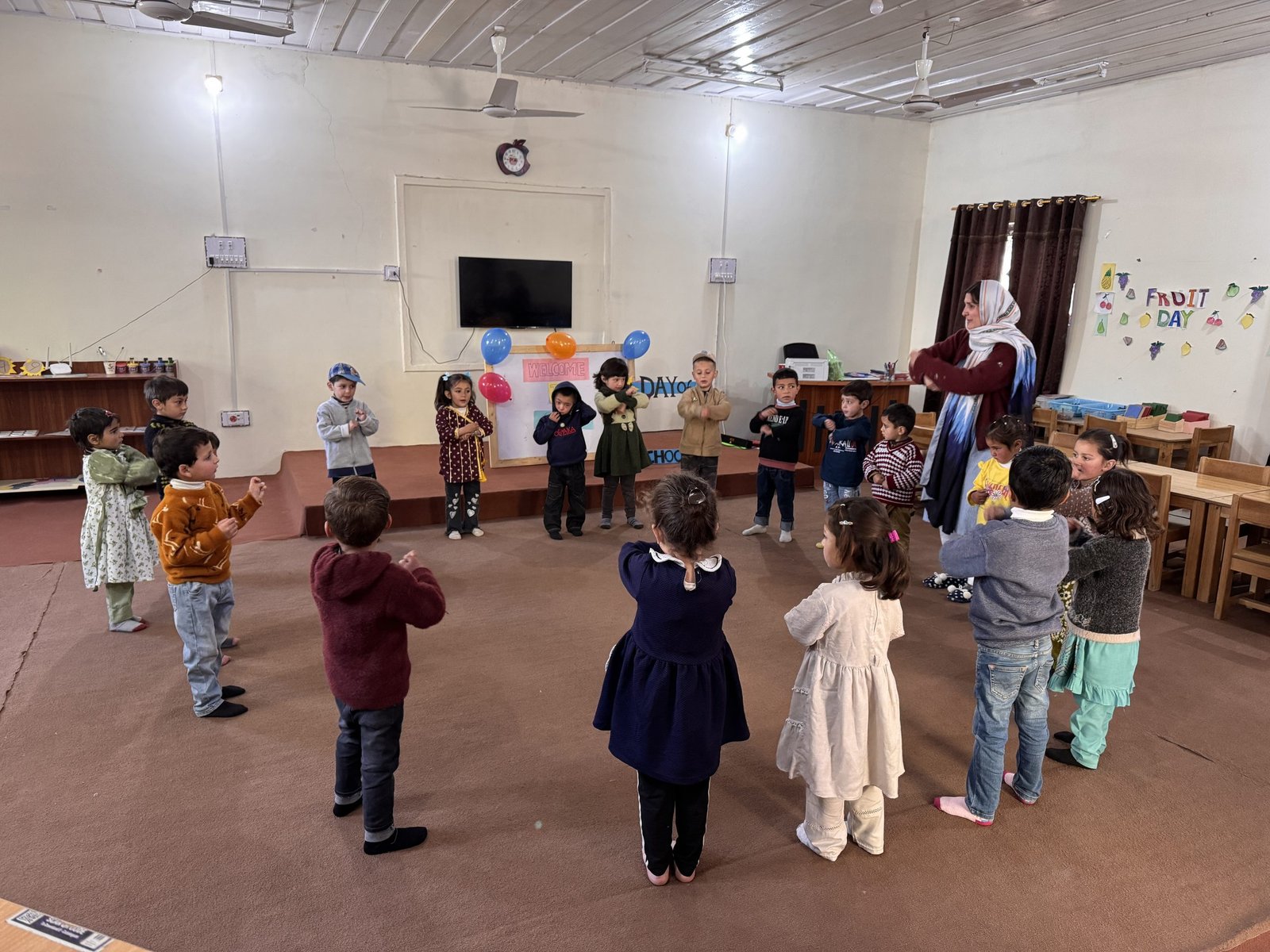 Children move together in a circle during a Fruit Day celebration.
